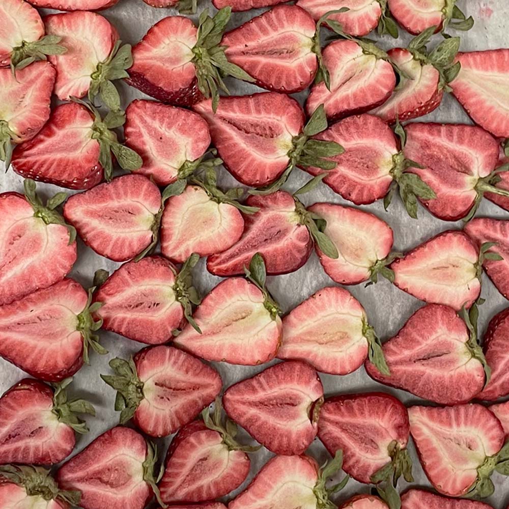 Rows of sliced freeze-dried strawberries sitting on a metal tray